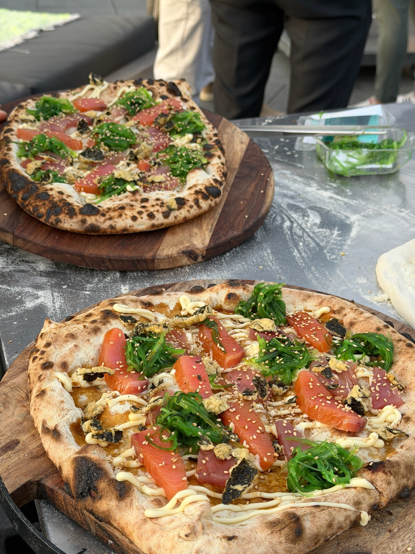 Pizza's met zalm en zeewiersalade op houten planken